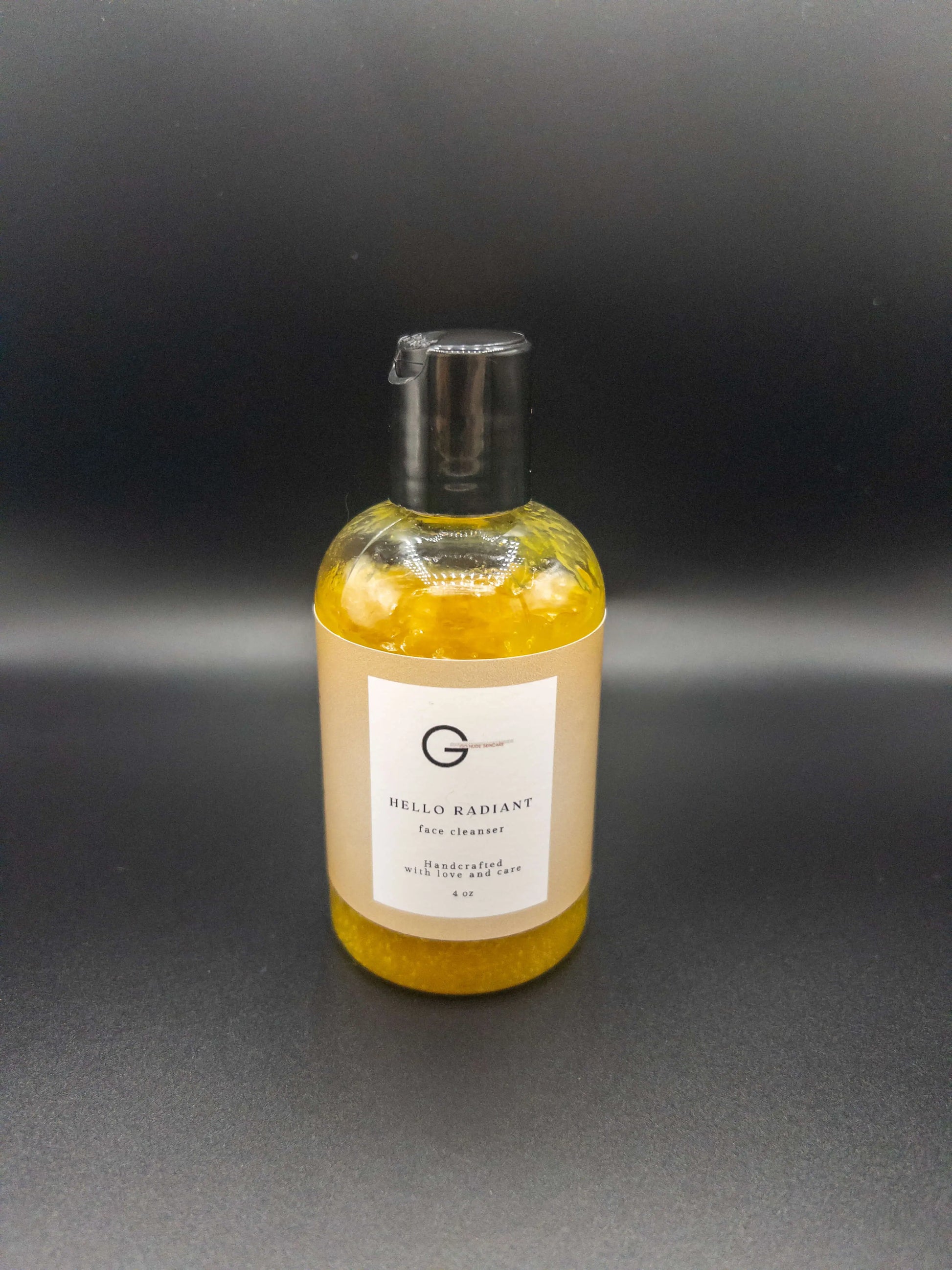 Picture of a 4 oz bottle of turmeric infused face cleanser for glowing skin on a black background.